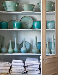 the shelves are filled with vases, dishes and other decorative items in blue hues