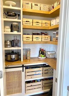 an organized pantry with wooden shelves and baskets