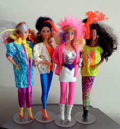 four barbie dolls are standing next to each other in colorful outfits and hair styles on display