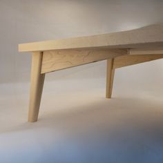 a wooden bench sitting on top of a white floor next to a light colored wall