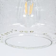 two yellow candles are in the middle of a clear glass bowl with water droplets on it