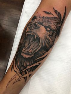 a man's arm with a bear and arrow tattoo design on the left forearm