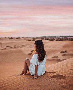 a woman sitting on top of a sand dune