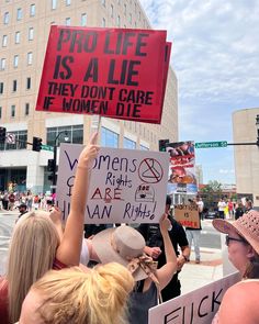 people holding signs and protesting in front of a building