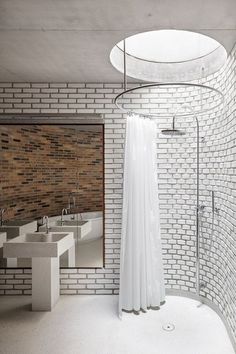 the bathroom is very modern and has white tile on the walls, along with two sinks