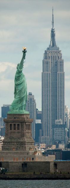 the statue of liberty stands in front of new york city's skyline