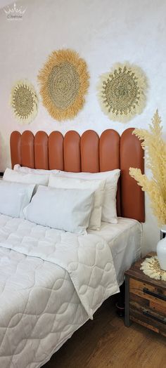 a white bed sitting next to a wooden table with two vases on top of it