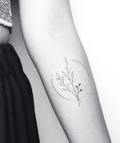 a woman's arm with a small flower tattoo on the left side of her arm