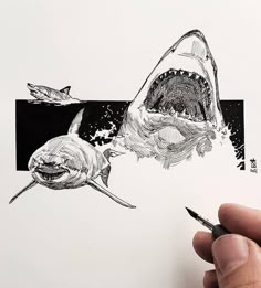 a hand holding a pen and drawing a shark with it's mouth open