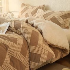 a bed with brown and white comforter next to a book on top of it