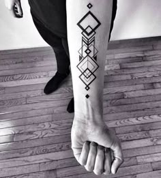 a black and white photo of a person's arm with a geometric tattoo on it