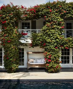 a bed sitting in the middle of a lush green garden next to a swimming pool