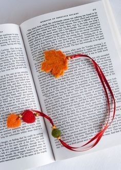 an open book with two tassels on it and a red string attached to the page