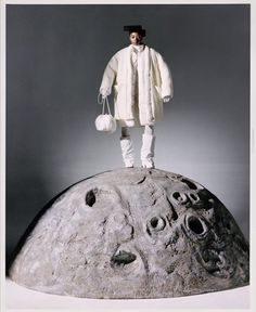 a man standing on top of a rock next to a white object in the shape of a moon