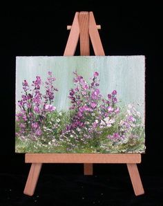 an easel with a painting of purple flowers on it