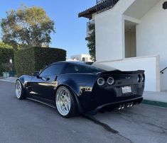 a black sports car parked in front of a house