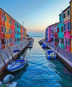 several boats are parked in the water next to colorful buildings on either side of each other