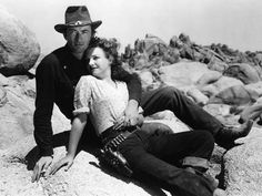 a man and woman sitting on rocks in the desert