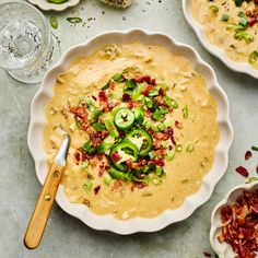 two bowls filled with dip and topped with bacon, jalapenos and green onions