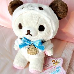 a white teddy bear with a blue ribbon around its neck sitting on a pink blanket