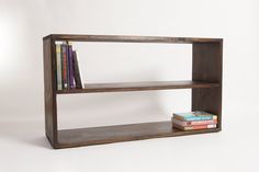 a book shelf with two books on top and one sitting on the bottom, in front of a white background