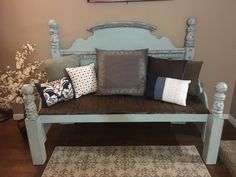 a wooden bench with pillows on it in front of a painting and carpeted floor