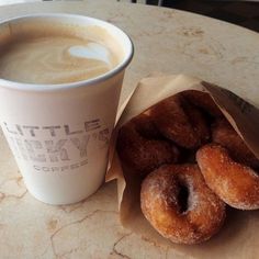 a cup of coffee and some doughnuts sitting on a table next to each other