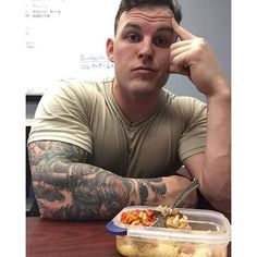 a man sitting at a table with a container of food in front of his face