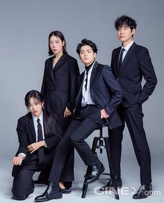 three people in suits and ties are posing for a photo with one person sitting on a stool