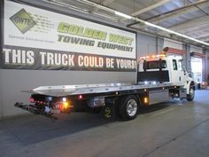 a tow truck parked in front of a building with a sign on the wall that says, this truck could be yours