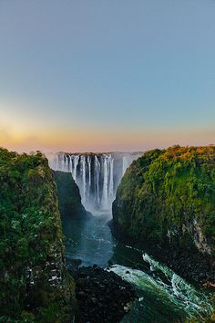 the sun is setting over a large waterfall