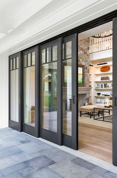 an open glass door leading into a room with tables and chairs on the outside wall