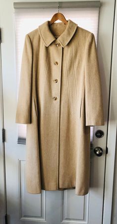 "We cannot find a tag that says the materials used but it seems to be wool. It's a very warm coat. There are a couple of spots that are missing material as shown in the photos. Please see the photos for more details. We disclose as much as we know about an item. Our items are vintage, gently used pieces, (with the exception of a few handmade products.) They may have flaws or wear. Check out the pictures to ensure you know what you are buying. All products are \"as is\" condition. If you are not Cream Long Wool Outerwear, Beige Wool Coat For Winter Tailoring, Beige Wool Coat For Tailoring, Beige Wool Coat With Buttons, Classic Long Beige Wool Coat, Beige Wool Coat With Button Closure, Vintage Wool Coat For Fall, Vintage Wool Long Coat, Vintage Wool Coat With Buttons For Formal Occasions