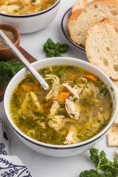 a bowl of chicken noodle soup with bread and parsley