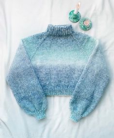 a blue and white sweater sitting on top of a bed