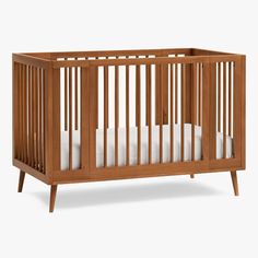 a wooden crib with white sheets in it