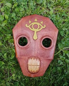 a wooden mask laying on top of green grass