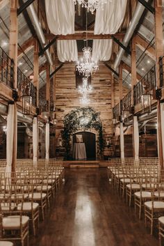 an indoor wedding venue with white chairs and chandelier hanging from the ceiling, surrounded by wood paneling