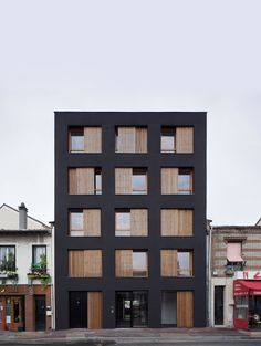 an apartment building with wooden shutters on the front and windows in the back, along with other buildings