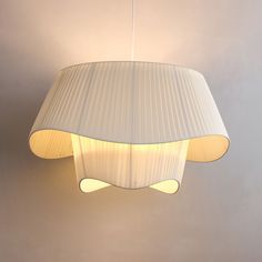 a white lamp hanging from the ceiling in a room with grey walls and flooring