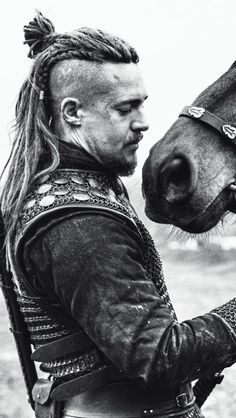 a man with dreadlocks is petting a horse