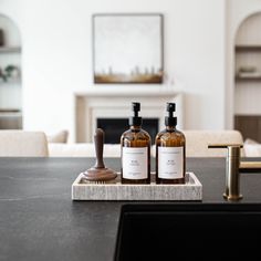 two bottles of soap and a brush sit on a counter in front of a fireplace