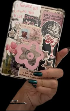 a person holding up a small album with stickers on it's cover and some flowers