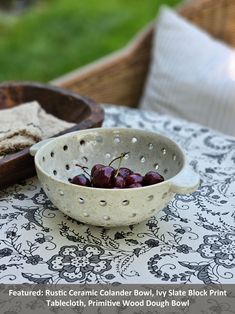 a bowl filled with cherries sitting on top of a table next to a plate