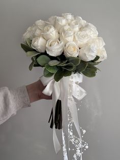 a person holding a bouquet of white roses