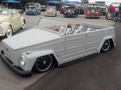 an old fashioned truck is parked in a parking lot with other cars and people looking at it