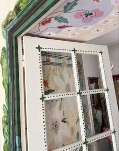 an old window is painted with flowers and leaves on the outside, and green trim around the edges