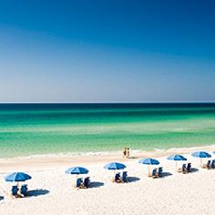 umbrellas and chairs are on the beach near the blue water in front of an ocean