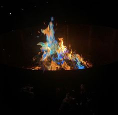 a fire pit is lit up in the dark with blue and orange flames on it