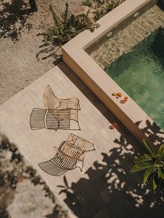 two chairs sitting next to a pool in the middle of a patio with tile flooring